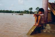 Überflutung: ein Kind sitz an einem Haus, um ihn nur Wasser